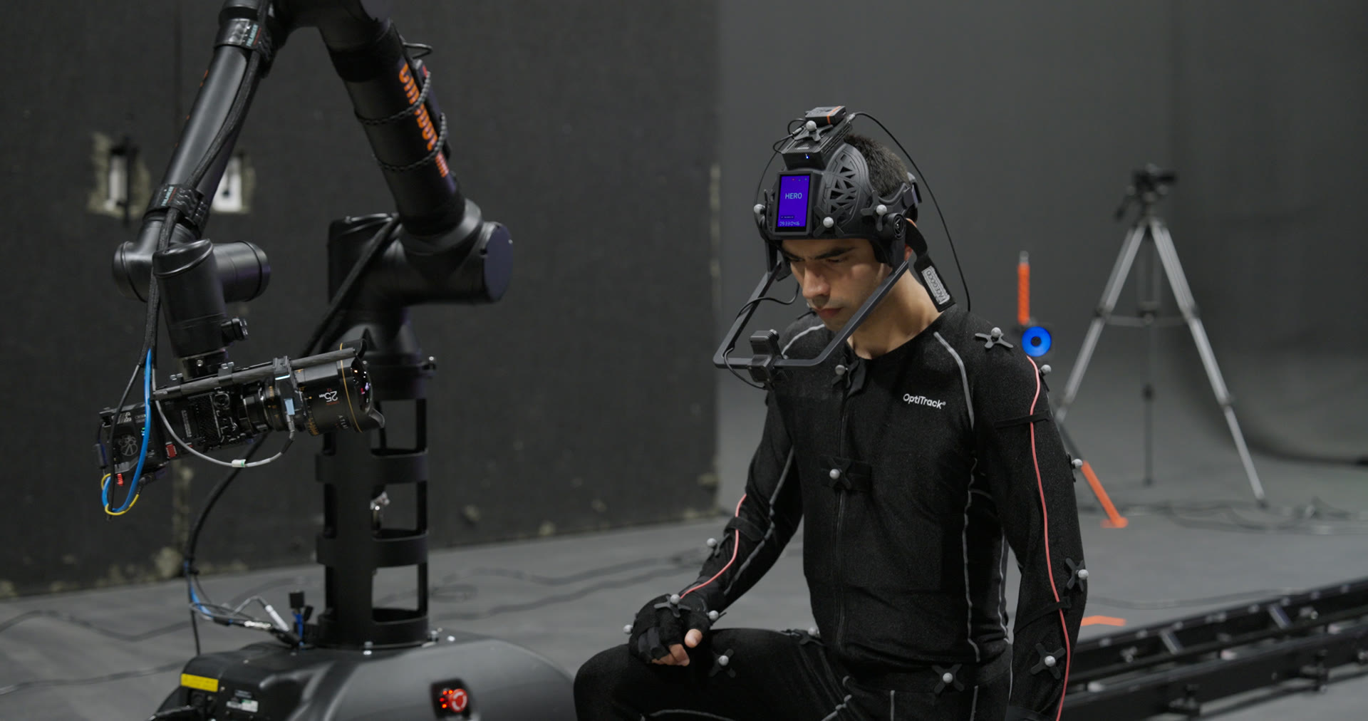 Performance capture shoot on the Atlanta stage — OptiTrack mocap suit and head-mounted facial rig beside the cinema robot